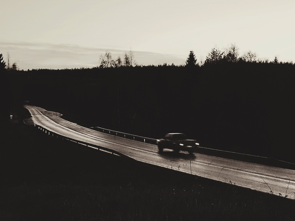 mustavalkoinen-tie-märkä-asfaltti-yksinäinen-auto-auto-ajaa-pois-päin-maisema